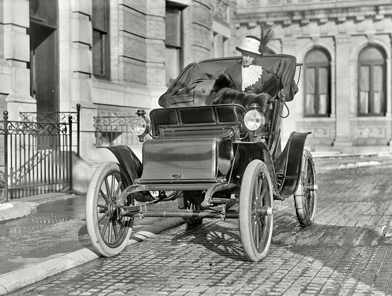Woman in vintage car on city street