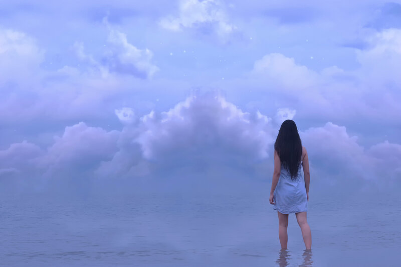 Woman in water under cloudy sky