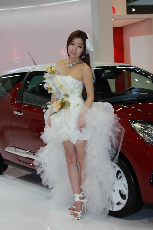 Woman in wedding dress at car show