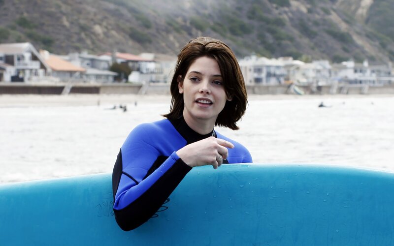 woman in wetsuit with surfboard