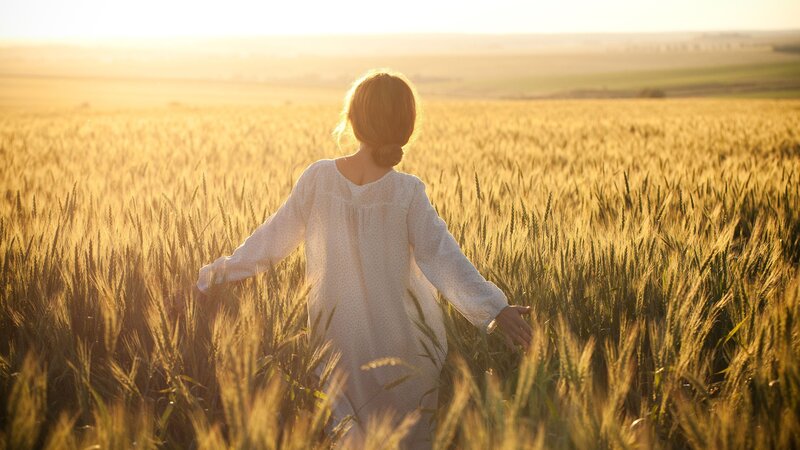 woman in wheat field at sunset