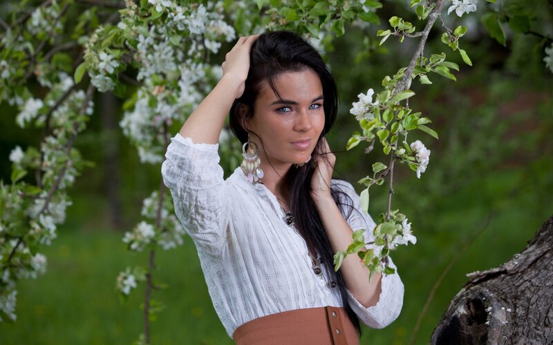 woman in white blouse by blossoming tree