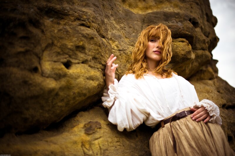 woman in white blouse by rock