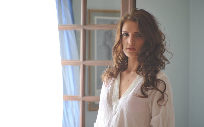 woman in white blouse by window