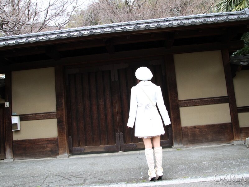 Woman in white coat at traditional gate