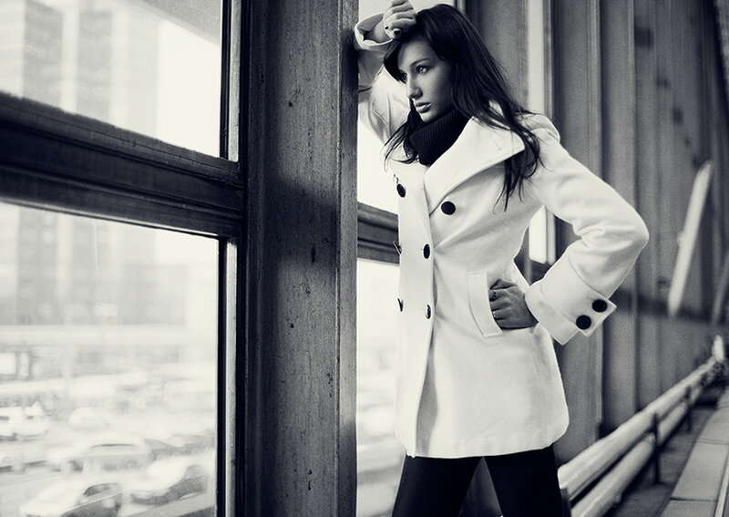 woman in white coat by window