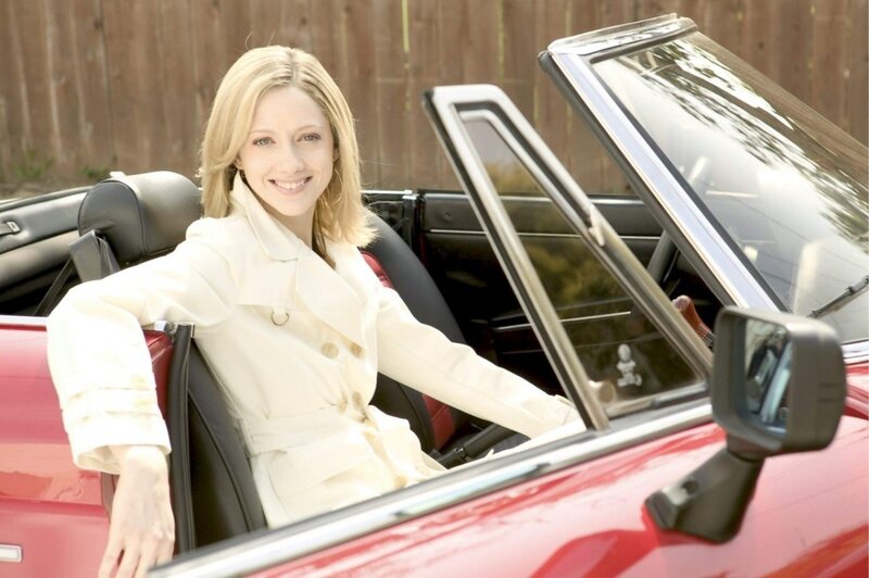 Woman in white coat in red convertible