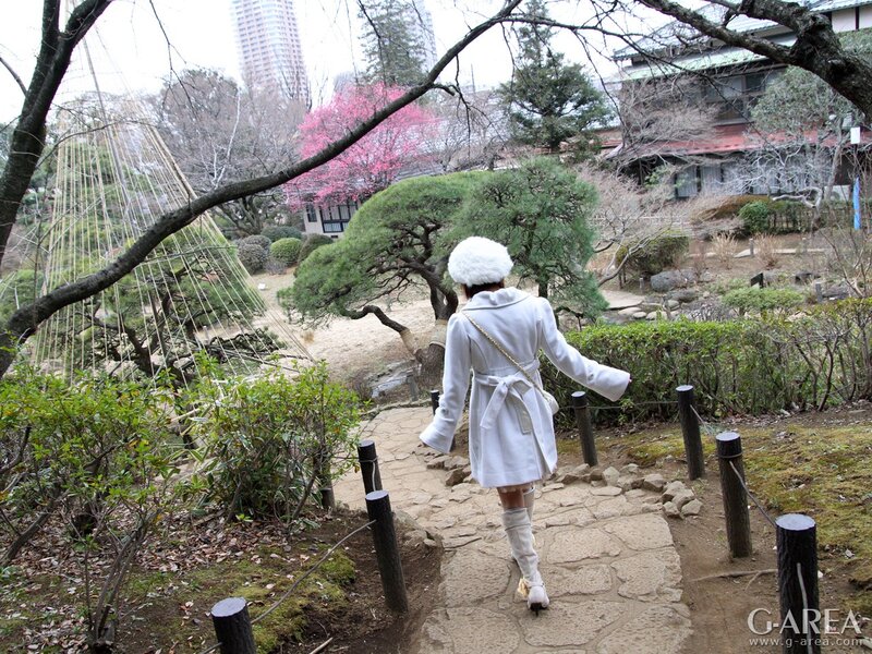Woman in white coat walking through garden
