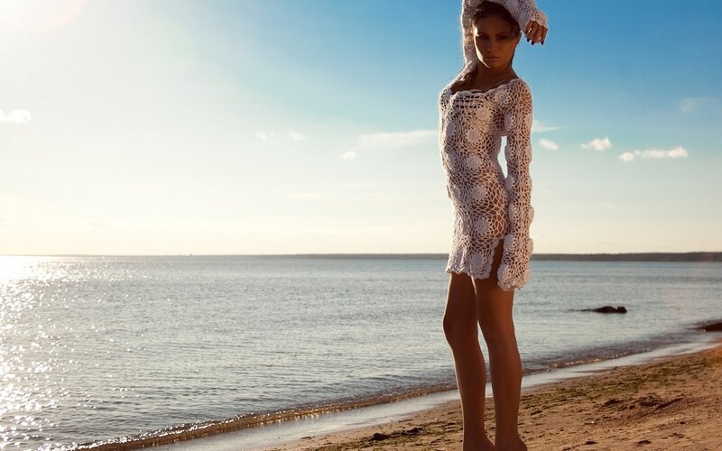 Woman in white crochet dress on beach