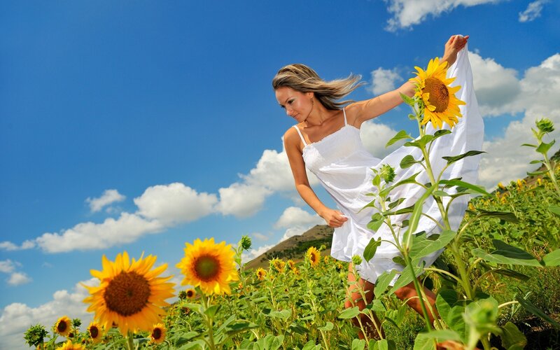 Woman in white dress among sunflowers