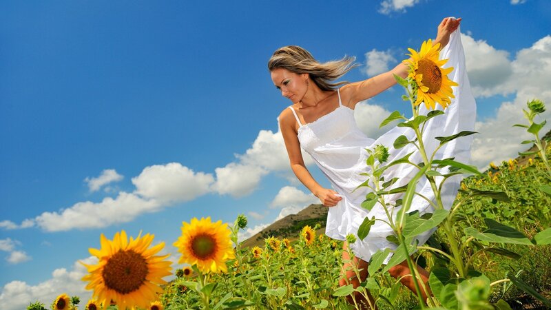 Woman in white dress among sunflowers