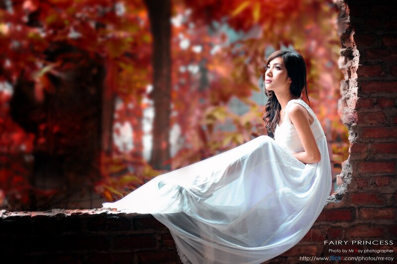 Woman in white dress by autumn leaves
