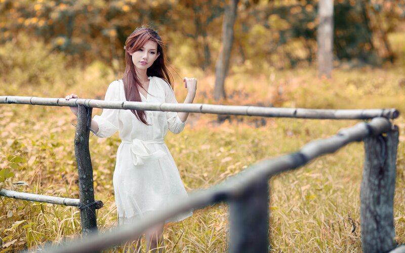 Woman in white dress by bamboo fence