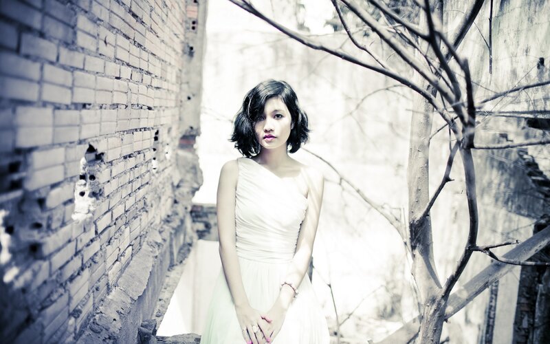 woman in white dress by brick wall
