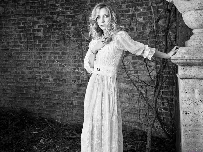 woman in white dress by brick wall