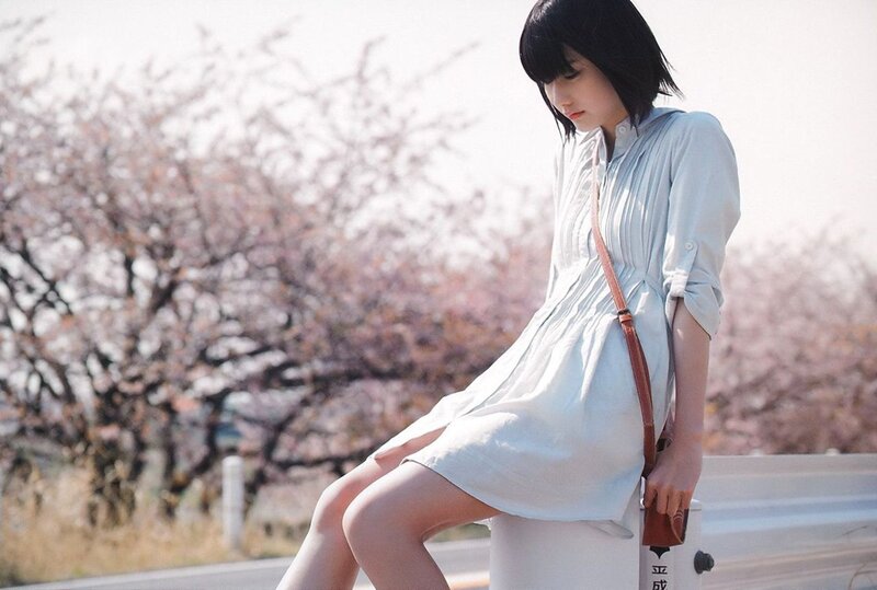 woman in white dress by cherry blossoms
