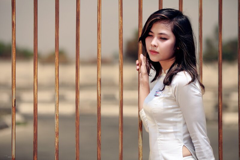 woman in white dress by fence