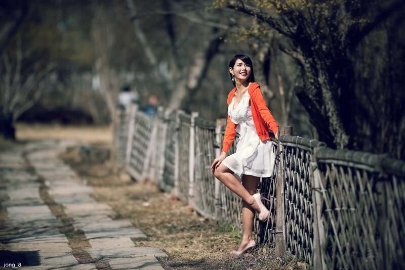 Woman in white dress by fence