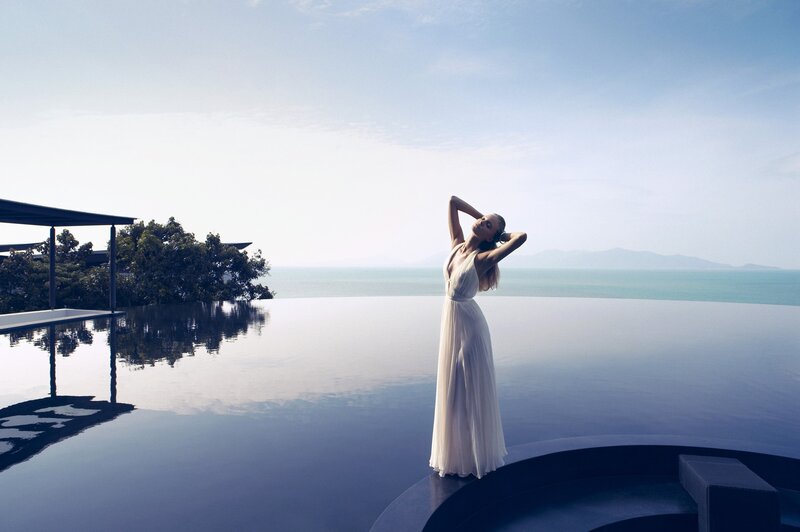 Woman in white dress by infinity pool