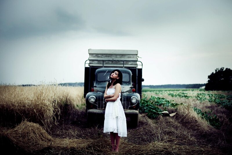 Woman in white dress by old truck