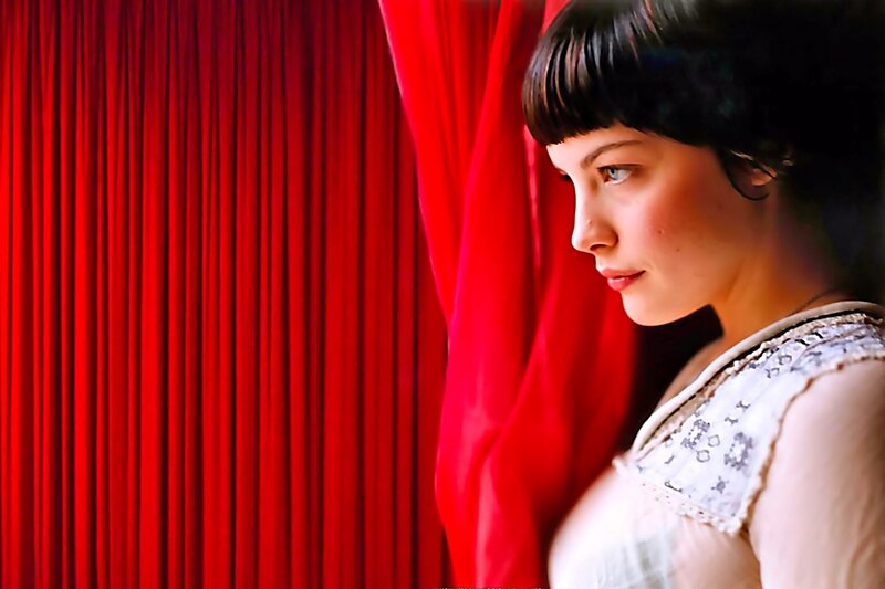 woman in white dress by red curtain