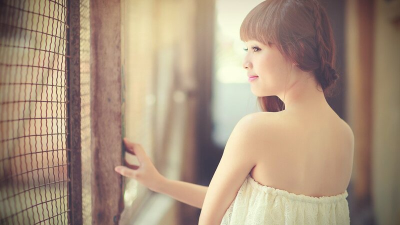 woman in white dress by window