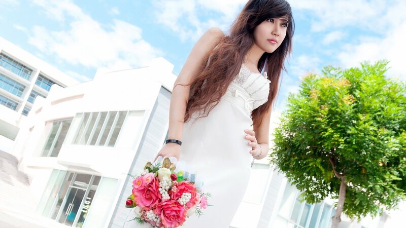 woman in white dress holding flowers