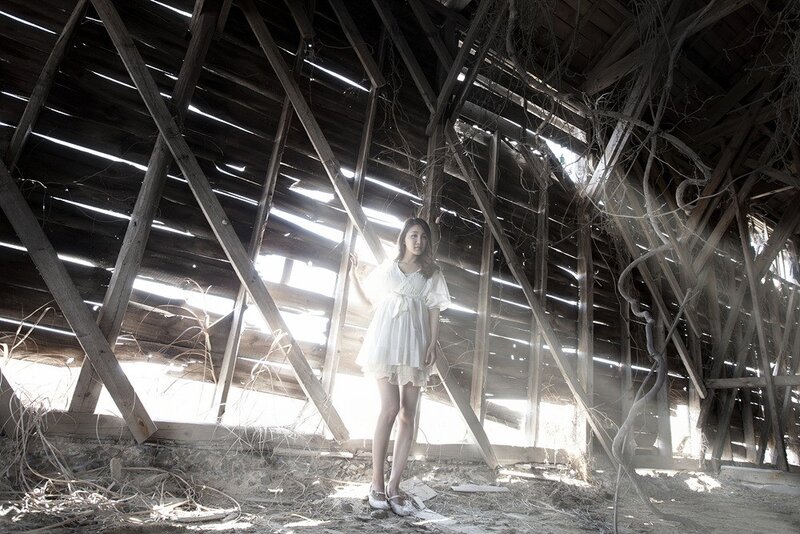 Woman in white dress inside old barn