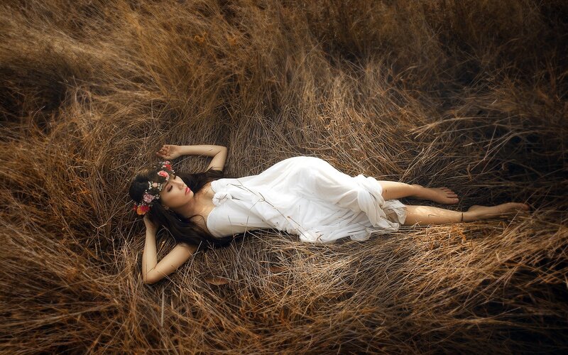 Woman in white dress lying in grass