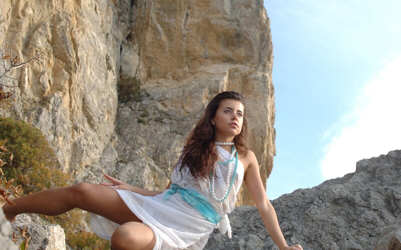 Woman in white dress on rocky cliff