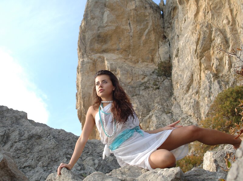 Woman in white dress on rocky cliff