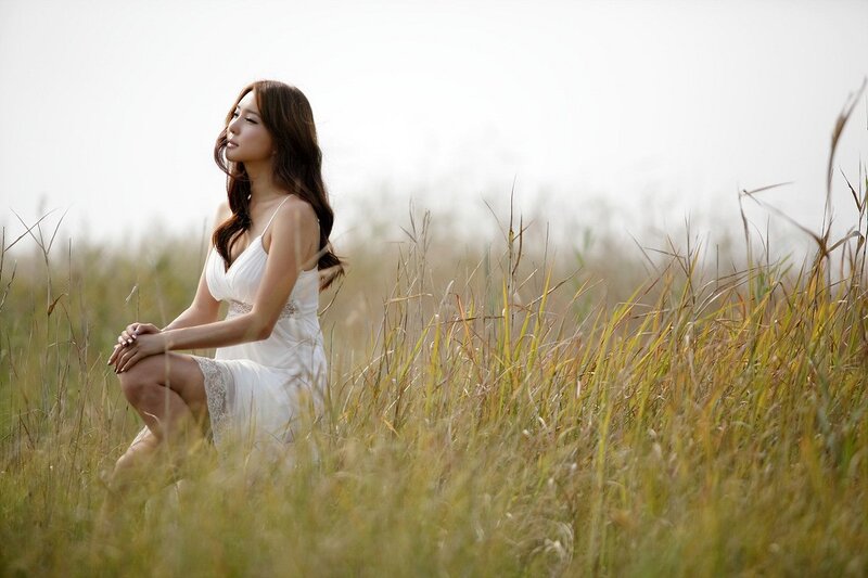 Woman in white dress sitting in field