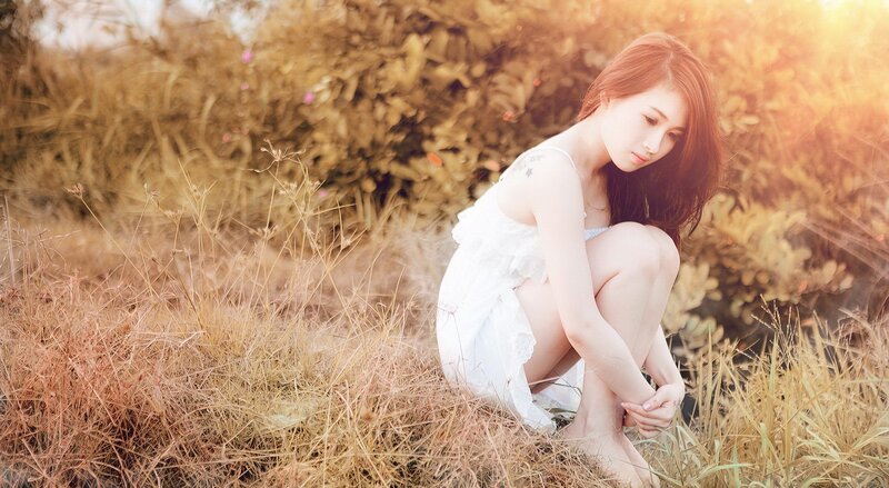 Woman in white dress sitting in field
