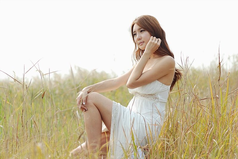 Woman in white dress sitting in field