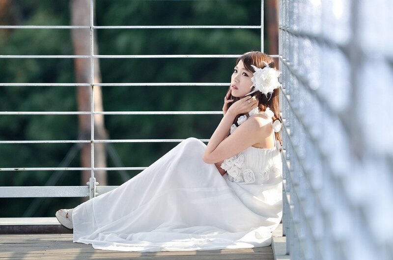 woman in white dress sitting on bridge