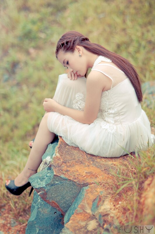 woman in white dress sitting on rock