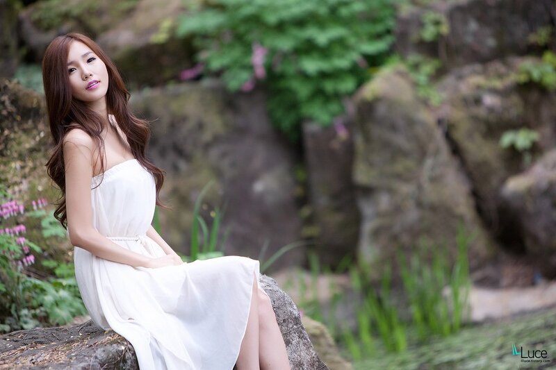 Woman in white dress sitting on rock