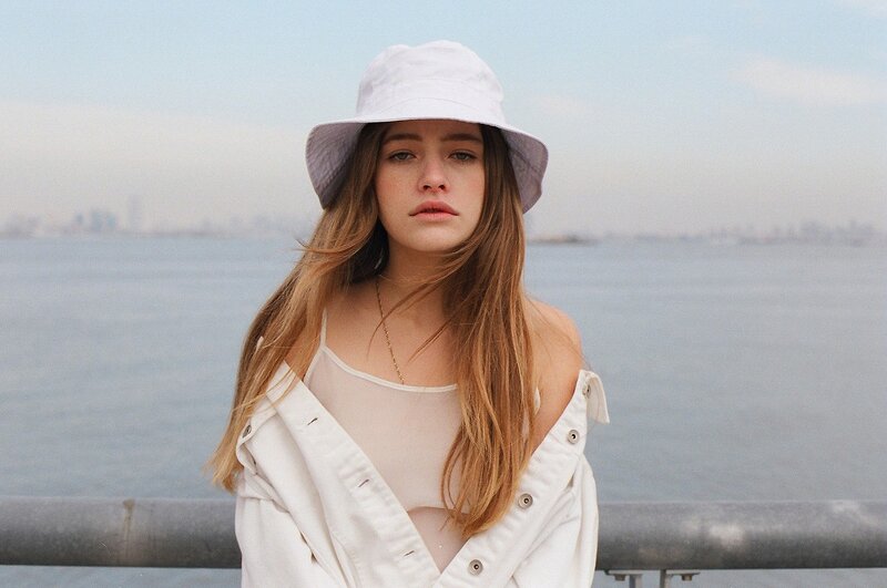 woman in white hat by the water