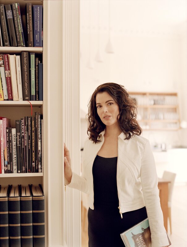 woman in white jacket by bookshelf