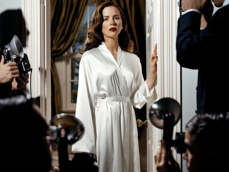 woman in white robe surrounded by photographers
