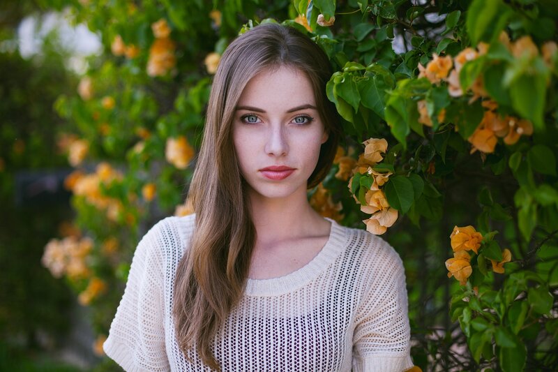 woman in white sweater by flowers