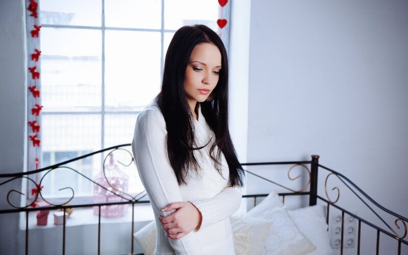 woman in white sweater by window