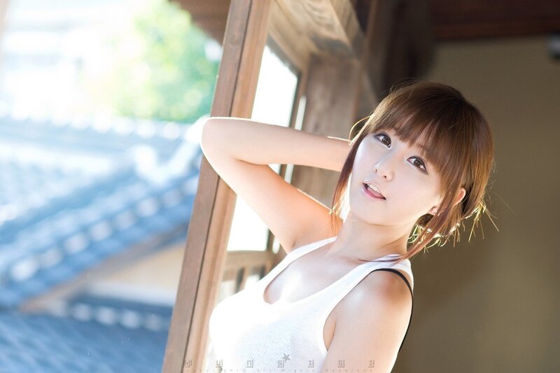 woman in white tank top by window