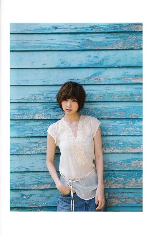 woman in white top against blue wall