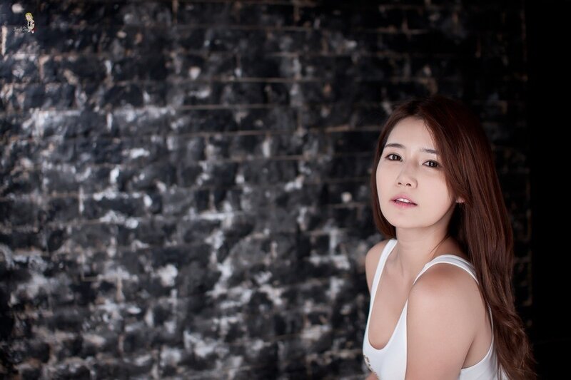 woman in white top against brick wall