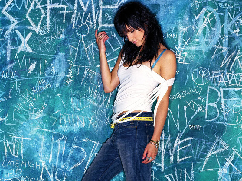 woman in white top against graffiti wall