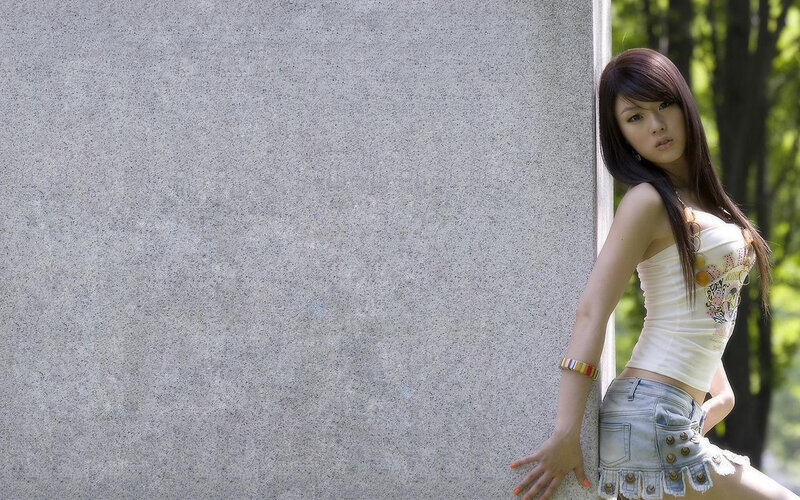 woman in white top leaning on wall