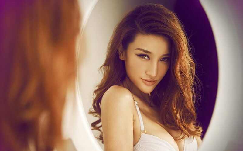 woman in white top looking at mirror