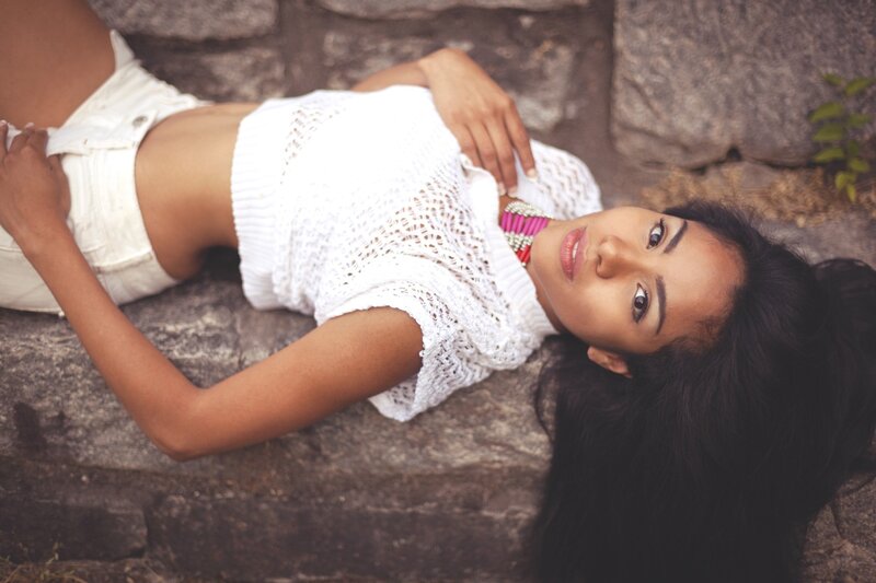 woman in white top lying on stone