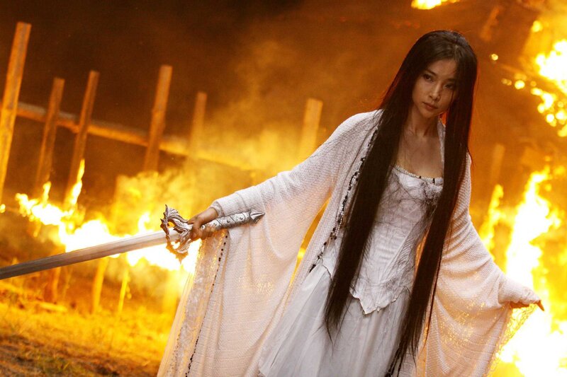 woman in white with sword in fire